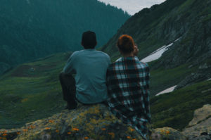 Couple sitting on a mountain looking out.