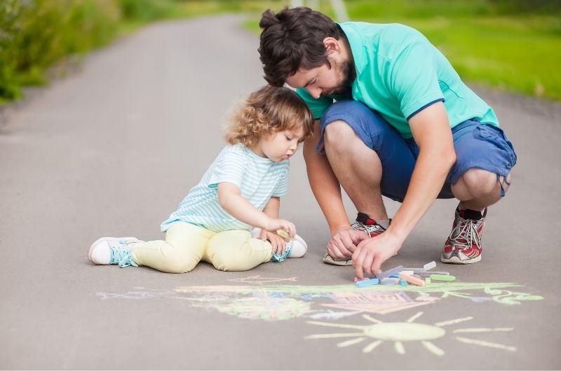 father and child with sidewalk chalk
