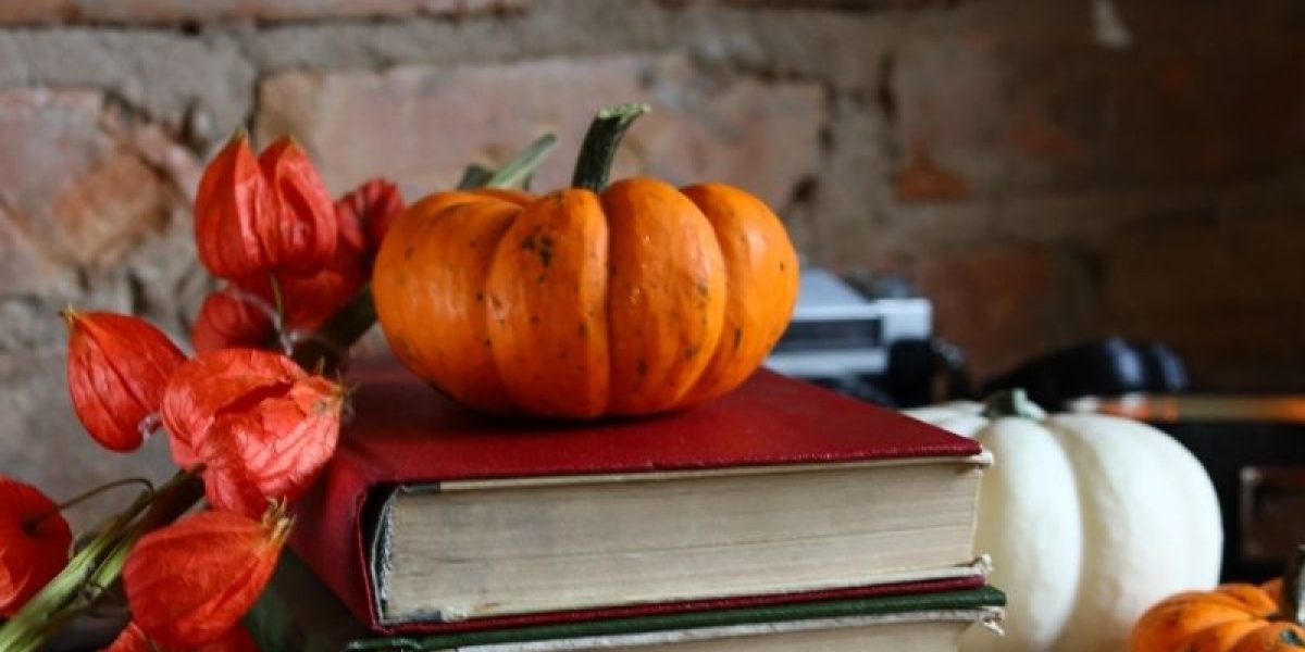 stack of books with pumpkins and fall foliage